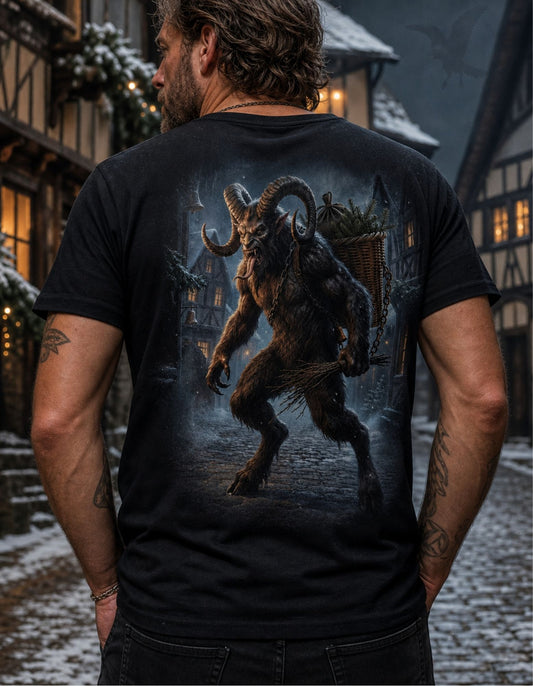 A man viewed from behind wearing a black graphic t-shirt with a large detailed print of a horned monster on the back, set against a snowy village street background.