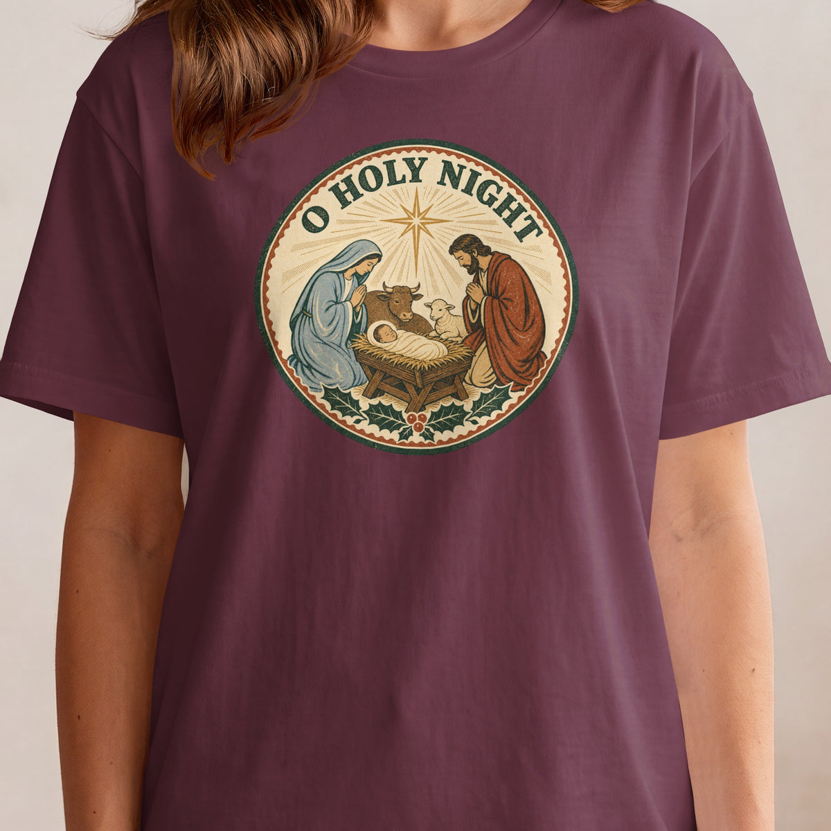 Nativity scene with "O Holy Night" text and star, on a maroon t-shirt.