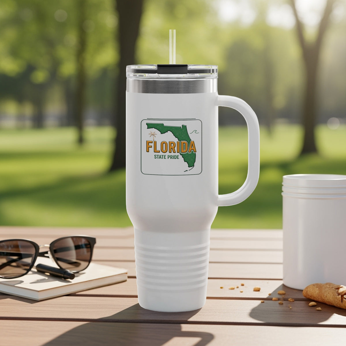 White tumbler with Florida State Pride logo and handle, on a table outdoors.