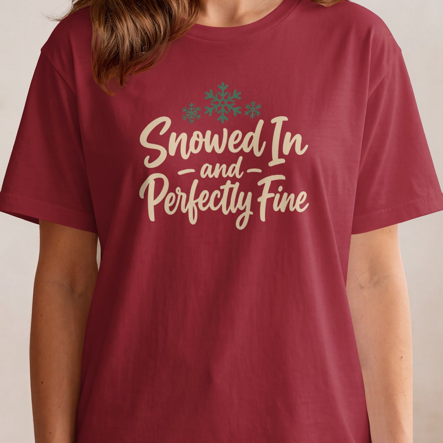 Maroon t-shirt with "Snowed In and Perfectly Fine" text and snowflake graphic.