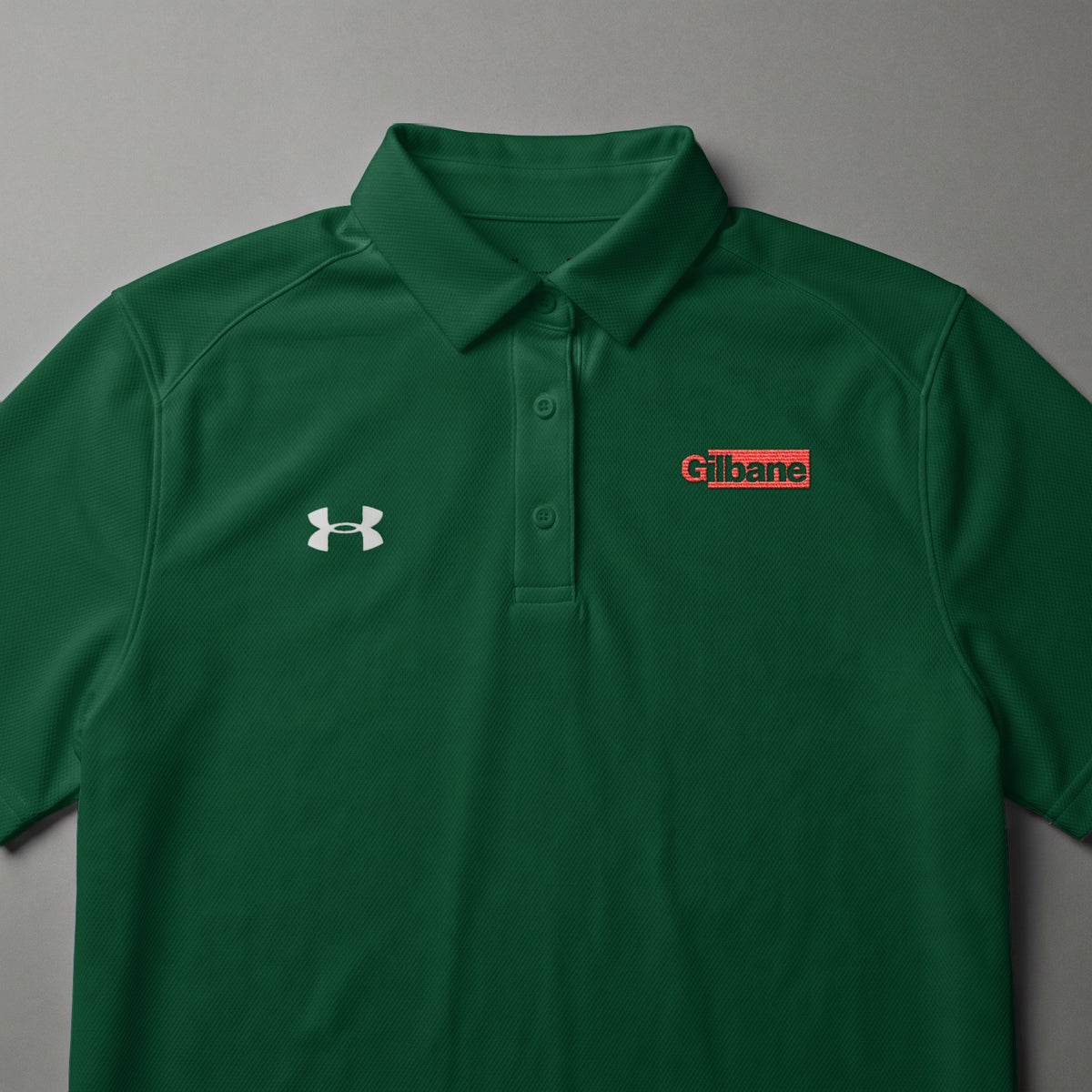 Green Under Armour polo shirt with Gilbane logo on the chest.