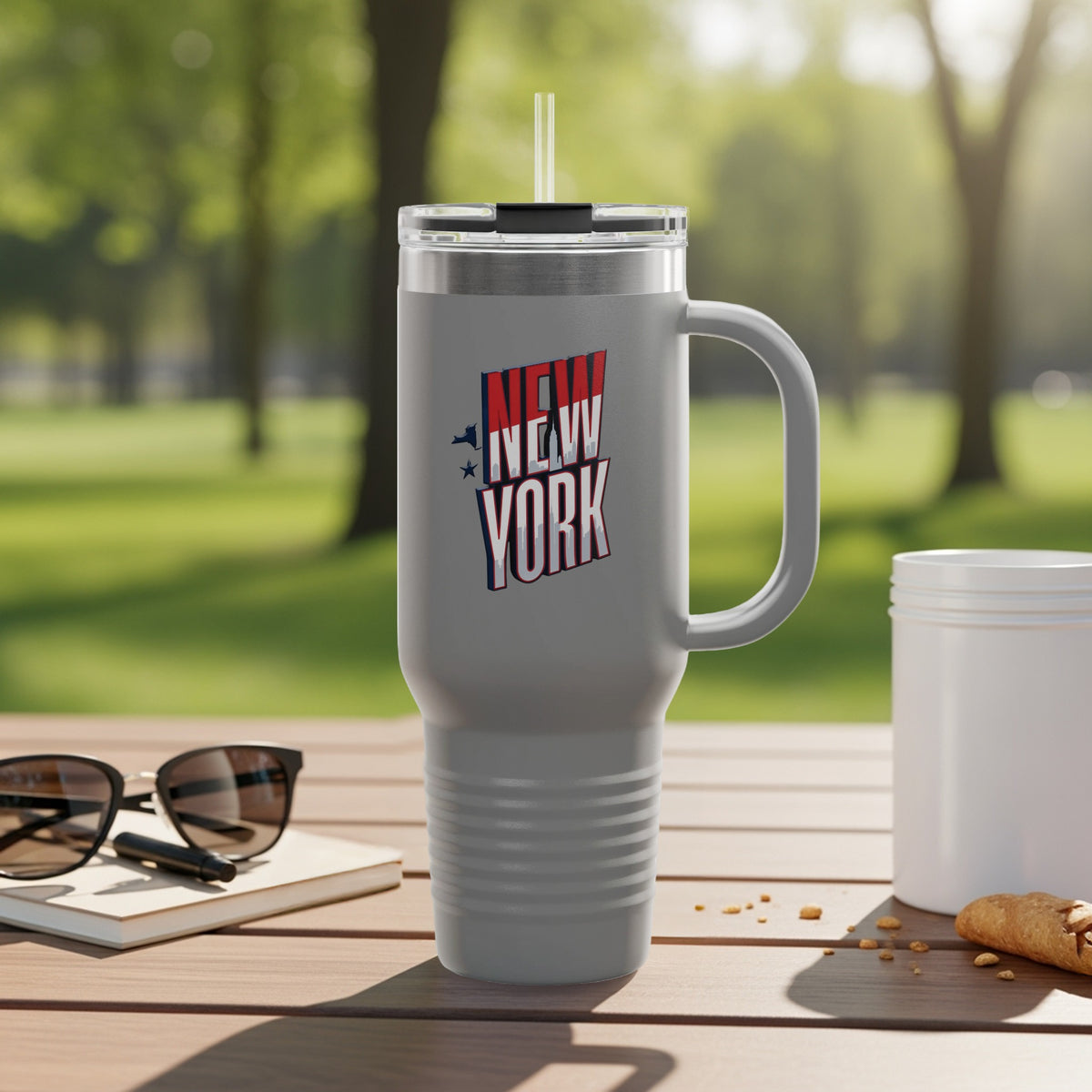 Gray travel mug with "New York" text and stars, on a table.