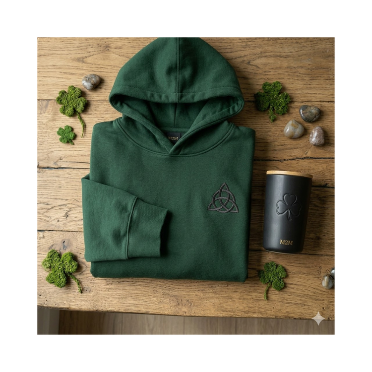Premium forest green hoodie and clover travel mug on a rustic wood background.