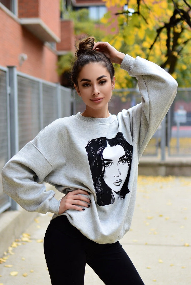 A fall background with a young woman wearing a graphic art sweatshirt.