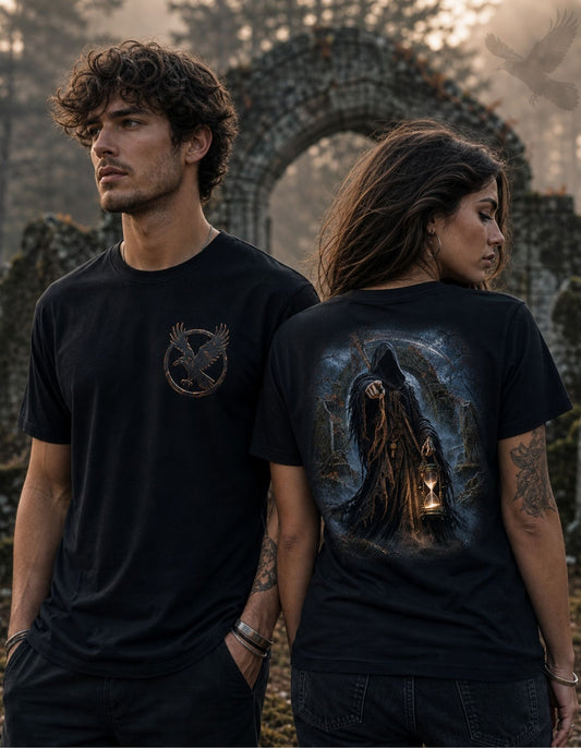 A man and a woman modeling black graphic t-shirts in an outdoor setting with a stone archway in the background. The man wears a black t-shirt with a small metallic gold mockingjay logo on the left chest.
