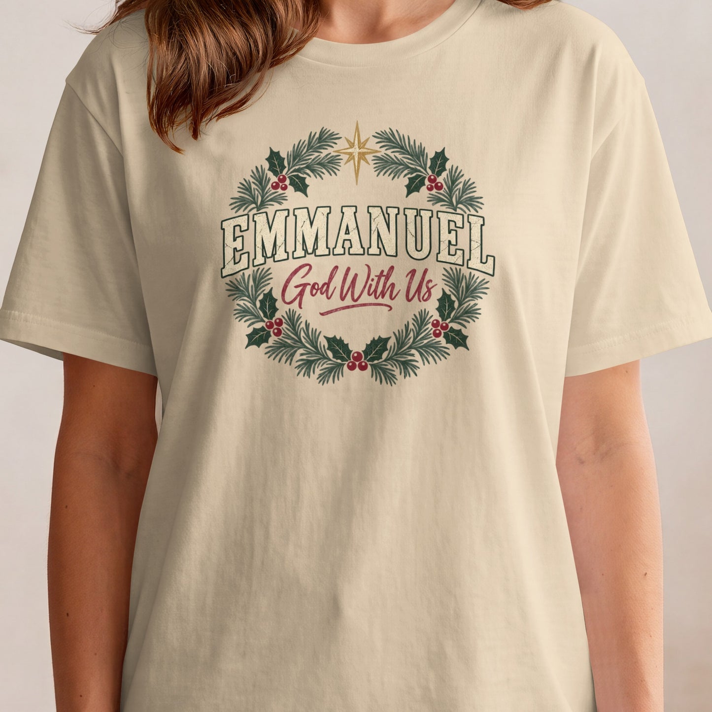 Light beige t-shirt with "EMMANUEL God With Us" text inside a festive wreath.