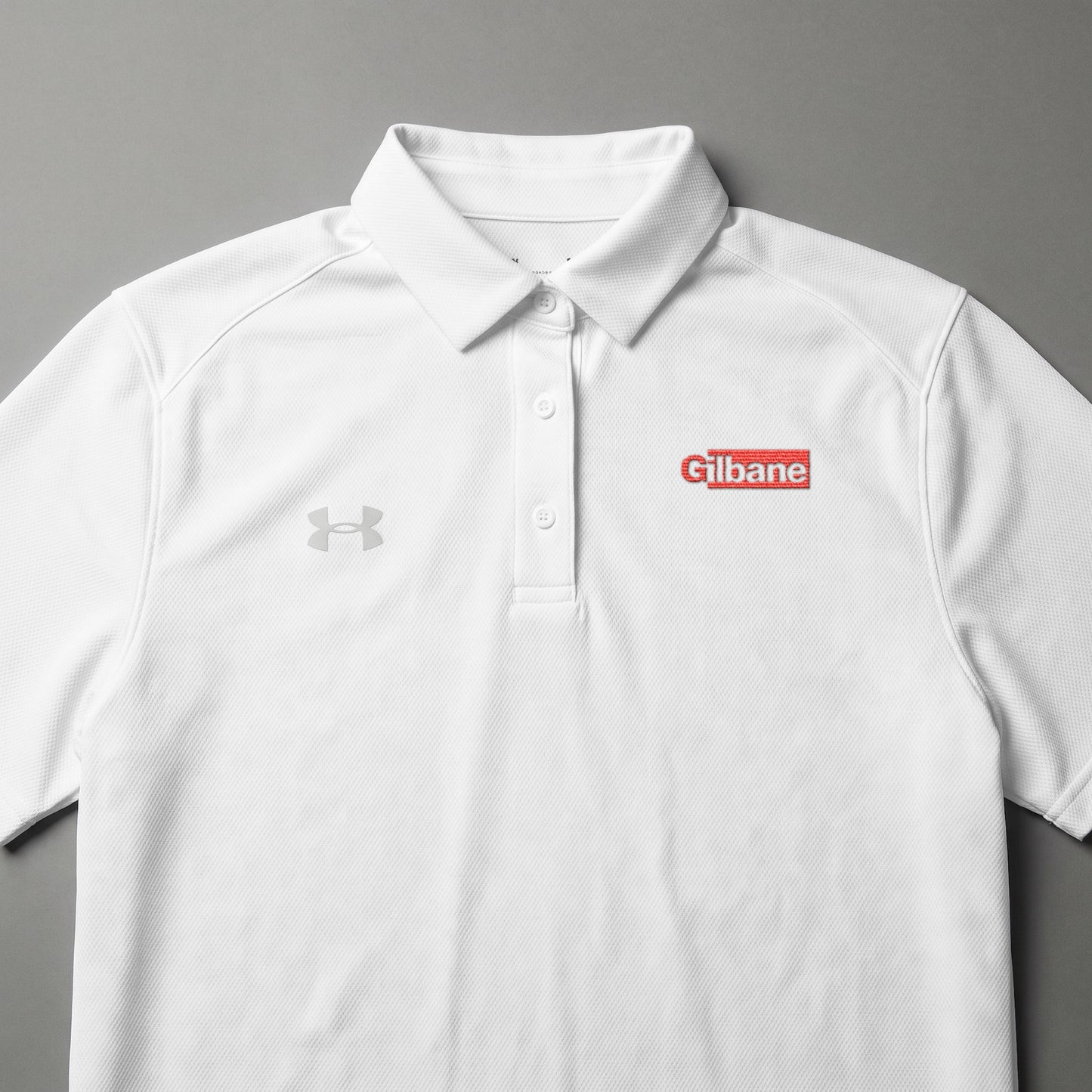White Under Armour polo shirt with red "Gilbane" logo on chest.