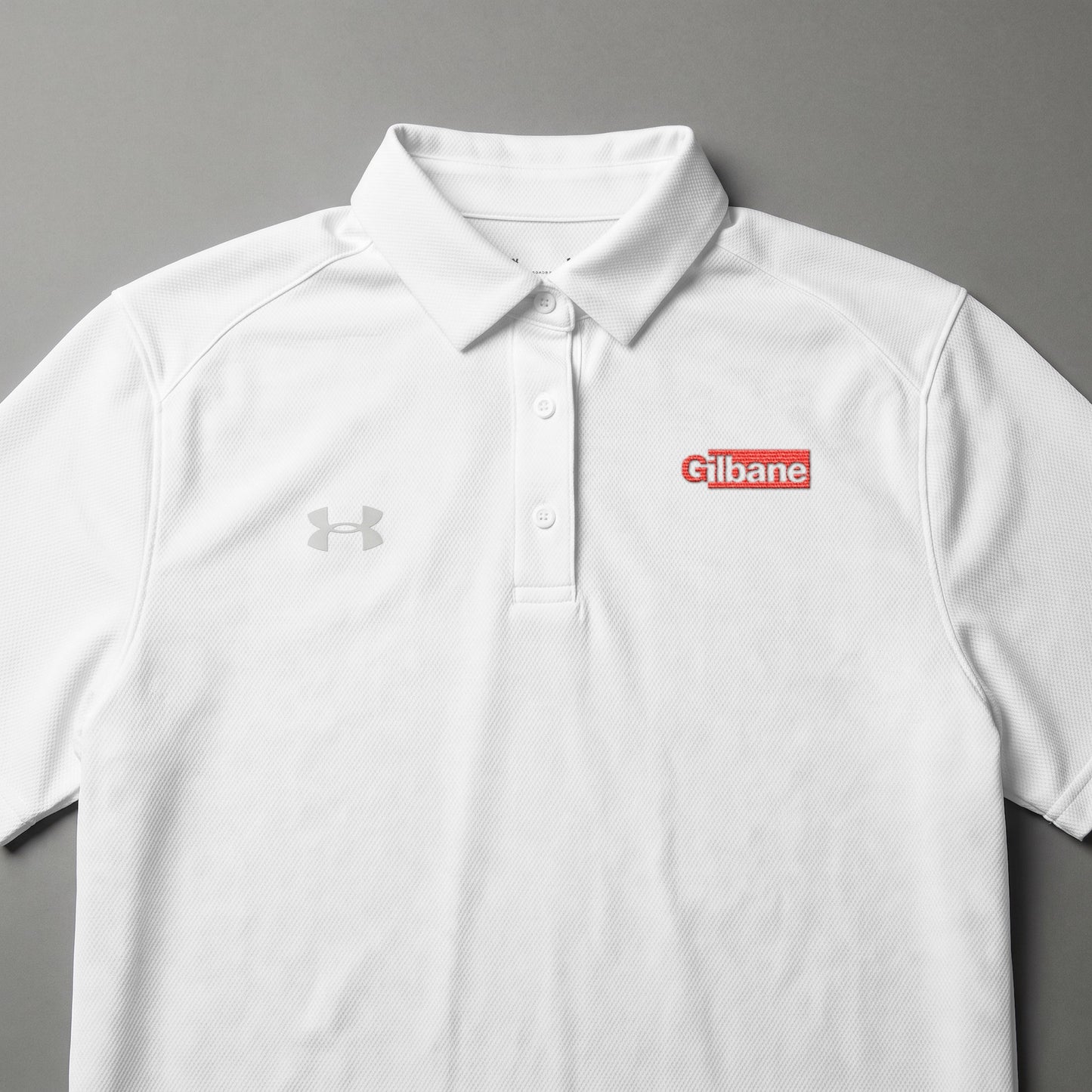 White Under Armour polo shirt with red "Cilbane" logo on left chest.