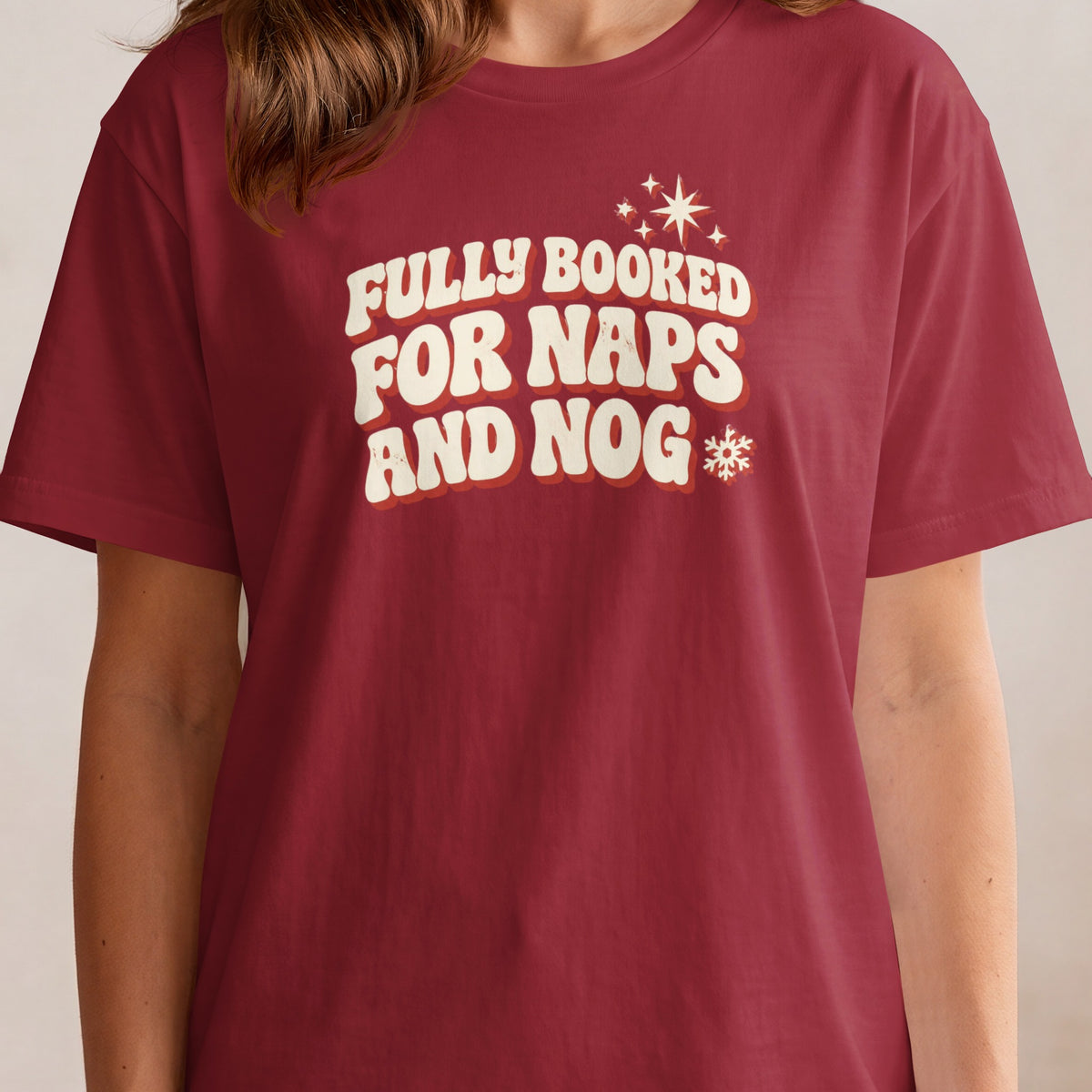 Maroon t-shirt with cream retro text "Fully Booked For Naps And Nog"