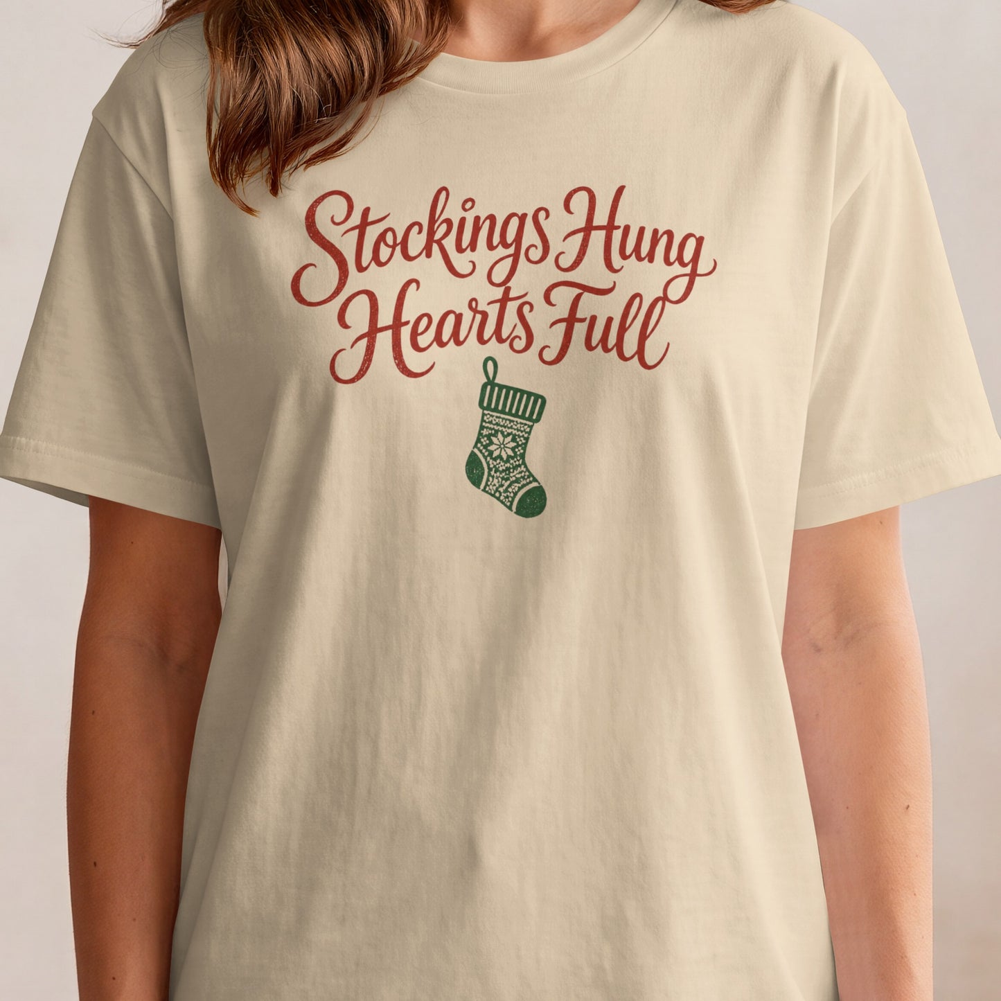Cream t-shirt with "Stockings Hung Hearts Full" text and Christmas stocking graphic.