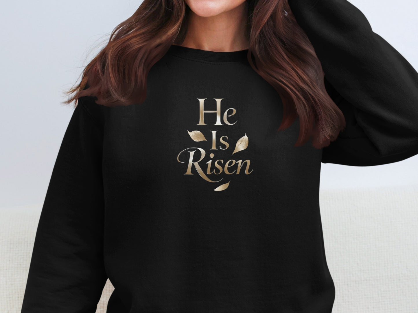 Black sweatshirt with "He Is Risen" text and gold leaves.