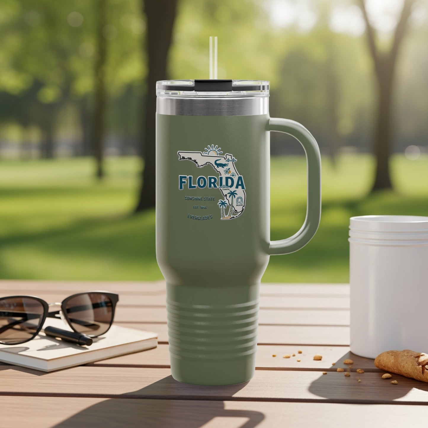 Green tumbler with Florida graphic and straw on a table outdoors.