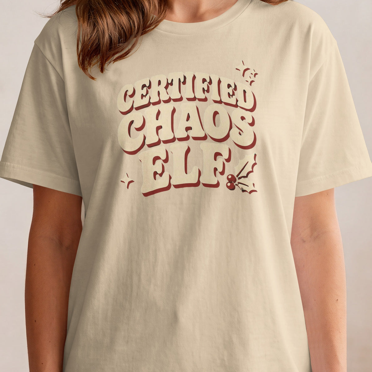 Light beige t-shirt with "Certified Chaos Elf" text and festive accents.