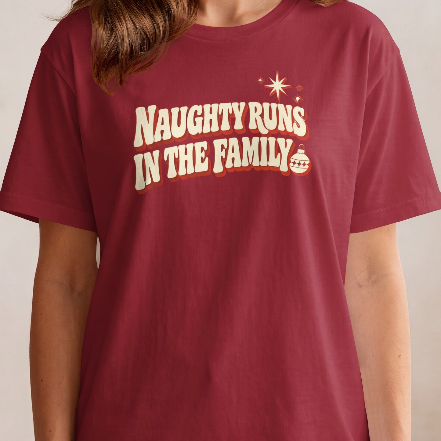 Red t-shirt with "Naughty Runs In The Family" text and Christmas ornament.