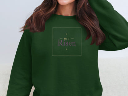 Dark green sweatshirt with "He is Risen" text and crosses.