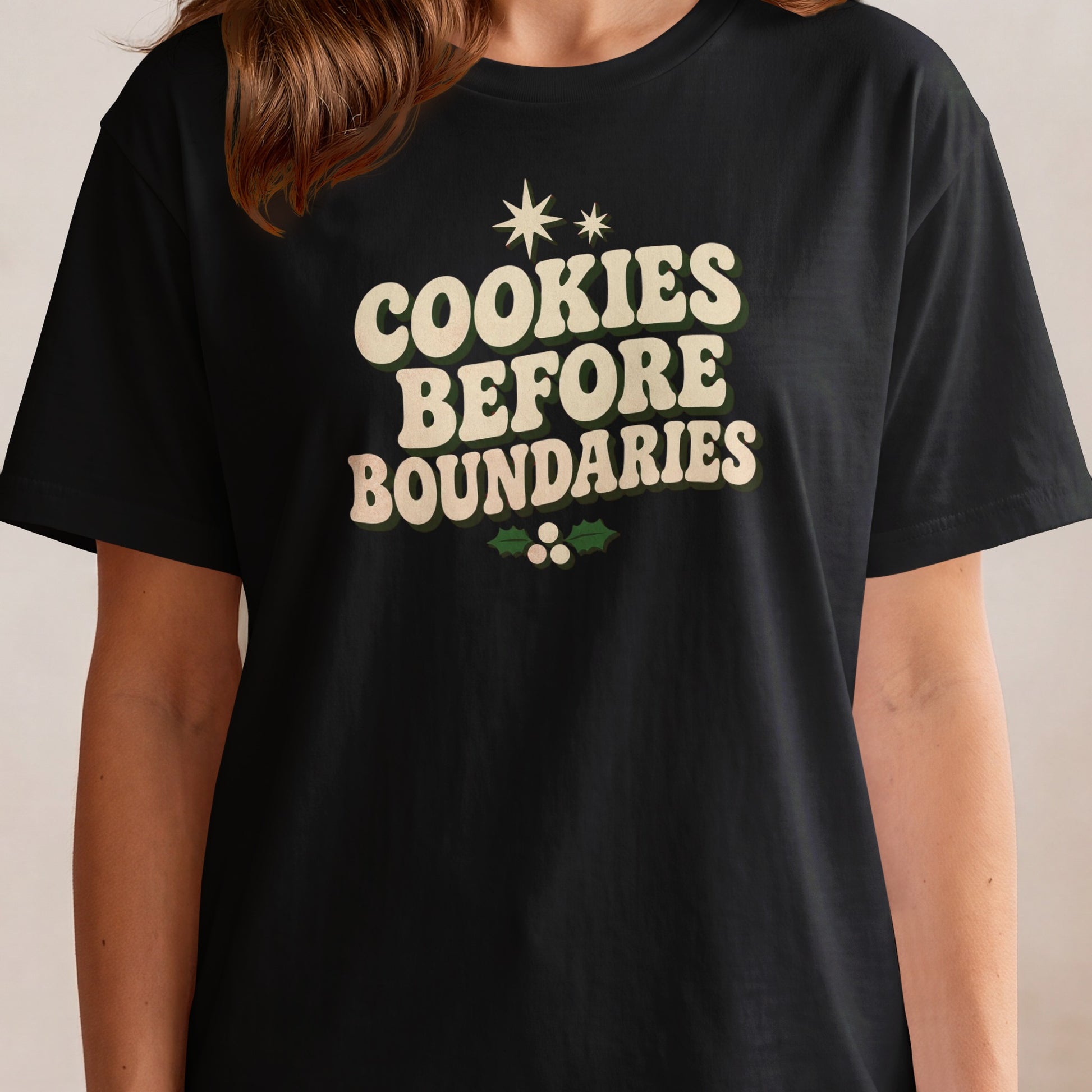 Black t-shirt with "Cookies Before Boundaries" text and festive holly accent.