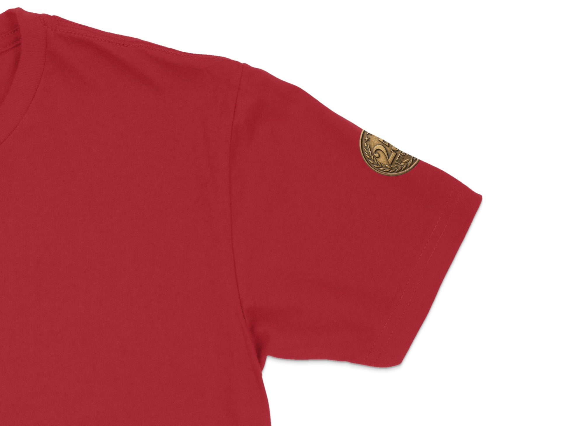 Red t-shirt sleeve with a circular embroidered gold emblem.