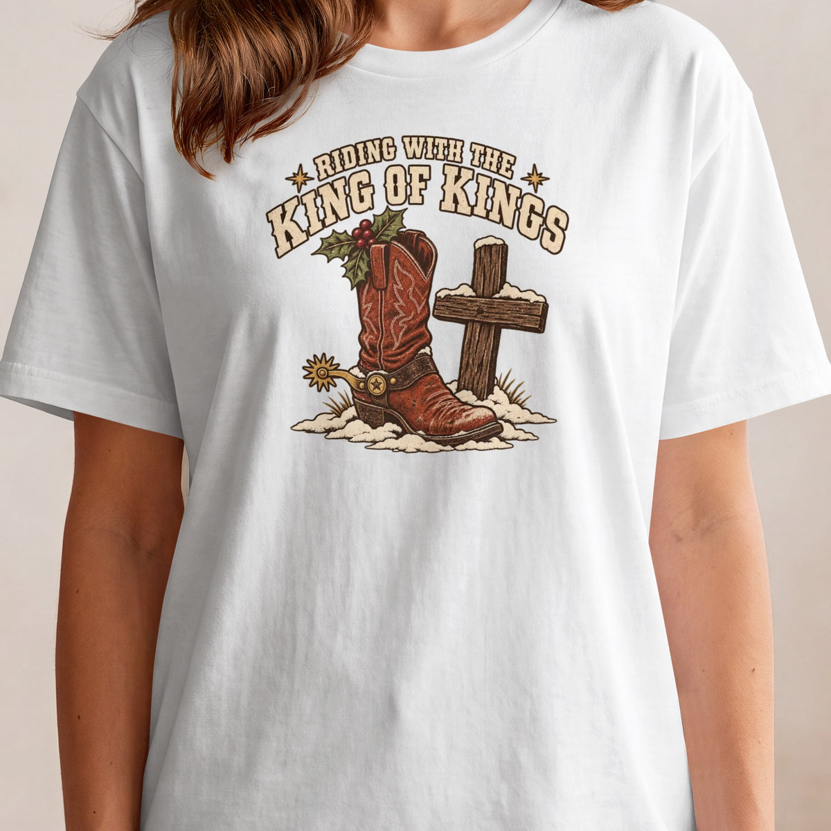 Cowboy boot with holly and a cross on a snowy ground, text reads "Riding with the King of Kings".