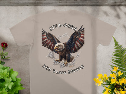 Tan t-shirt featuring an eagle breaking through a torn flag with "1776-2026 250 Years Strong" text.