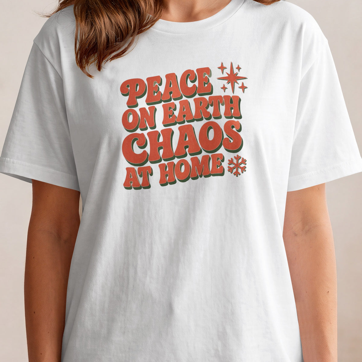 White t-shirt with text "Peace on Earth Chaos at Home" and holiday graphics.