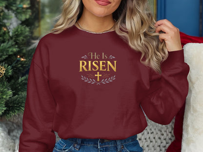 Maroon sweatshirt with "He Is Risen" text and laurel wreath design.
