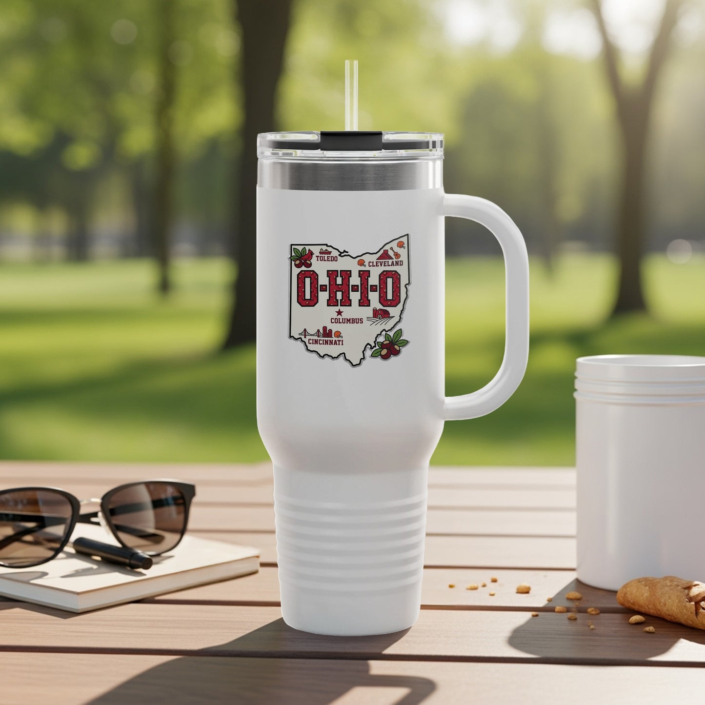 White tumbler with Ohio cities map and skyline graphic, resting on table.