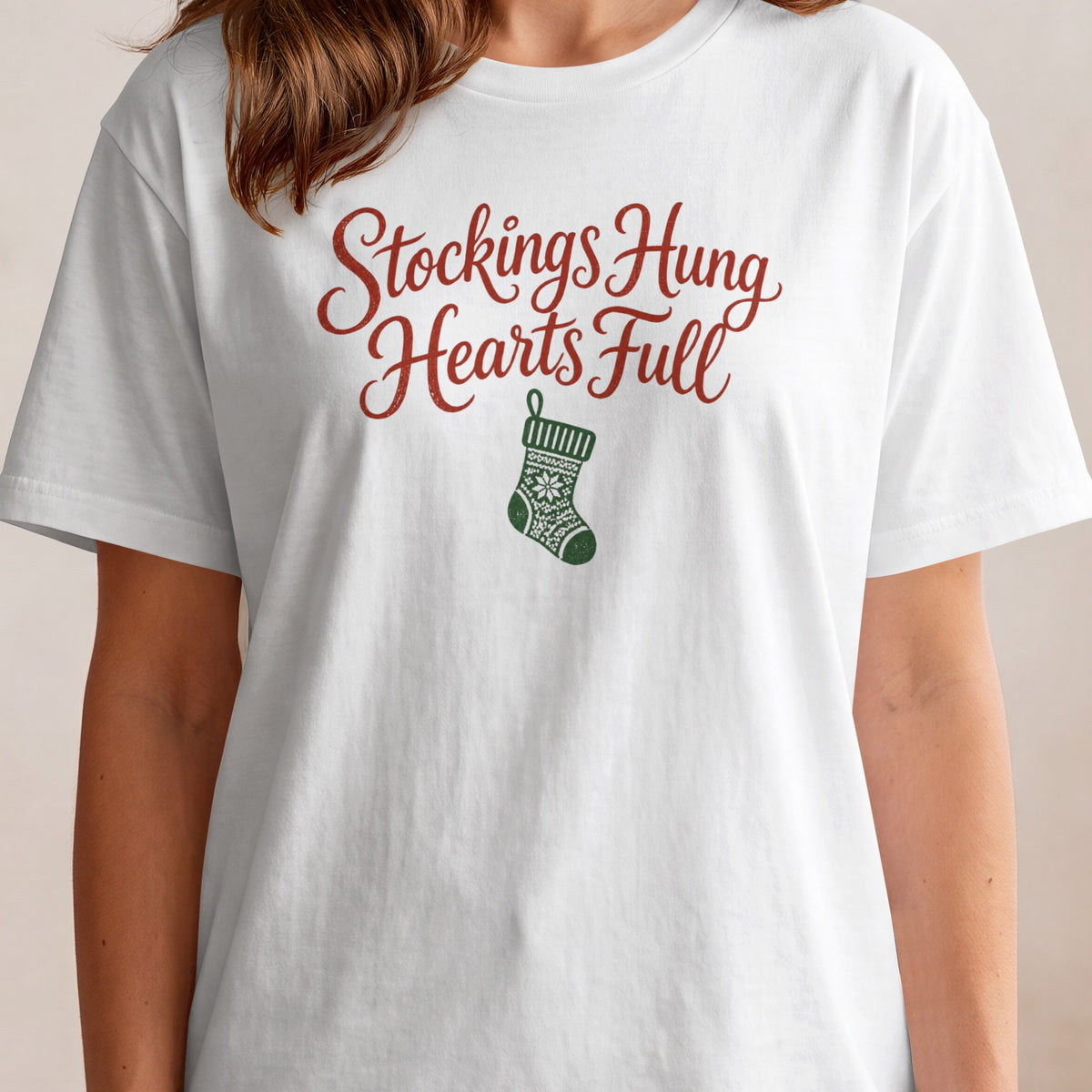 White t-shirt with red text "Stockings Hung Hearts Full" and green Christmas stocking graphic.