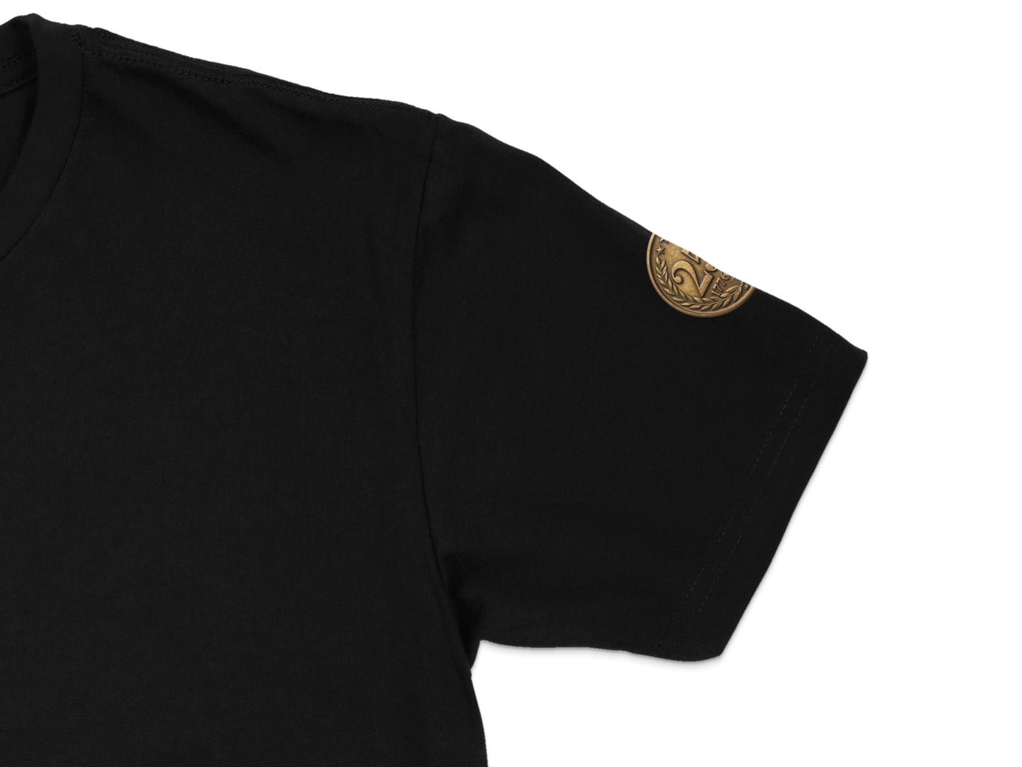 Black t-shirt sleeve with a small gold coin emblem on the bicep.
