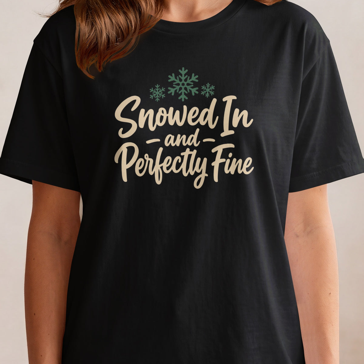 Black t-shirt with "Snowed In and Perfectly Fine" text and snowflakes.