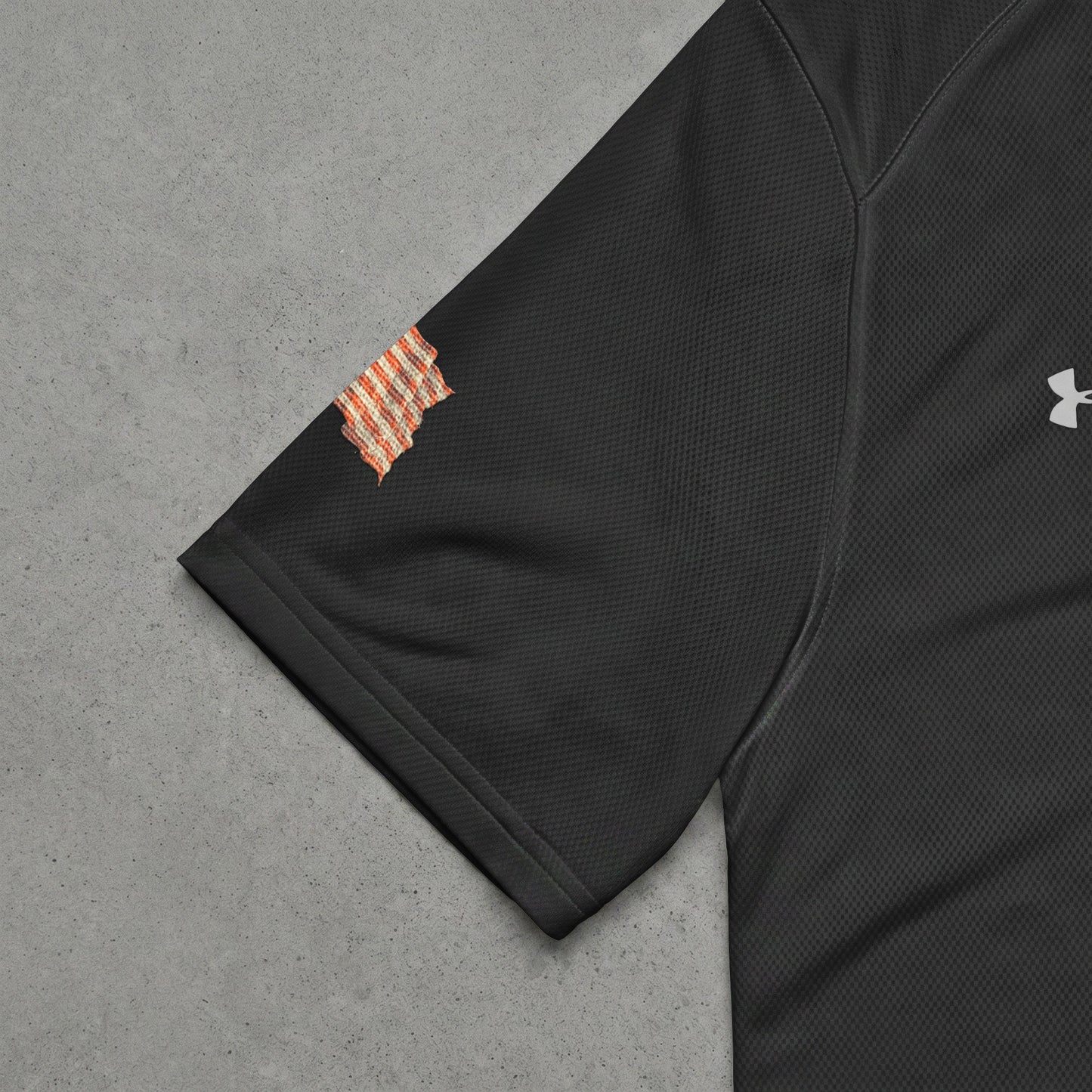 Black Under Armour t-shirt sleeve with orange checkered patch.