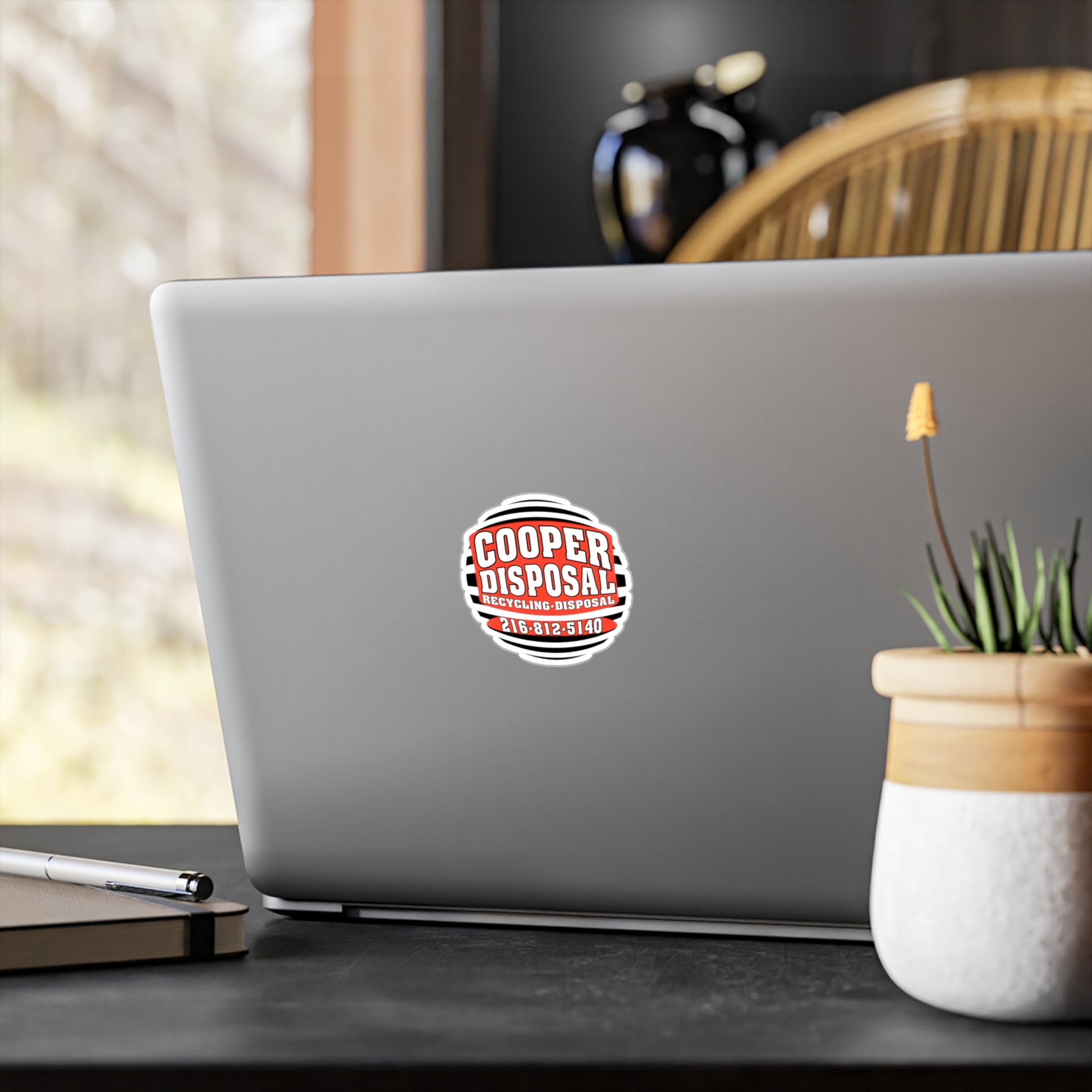 Cooper Disposal sticker with phone number on a laptop screen.