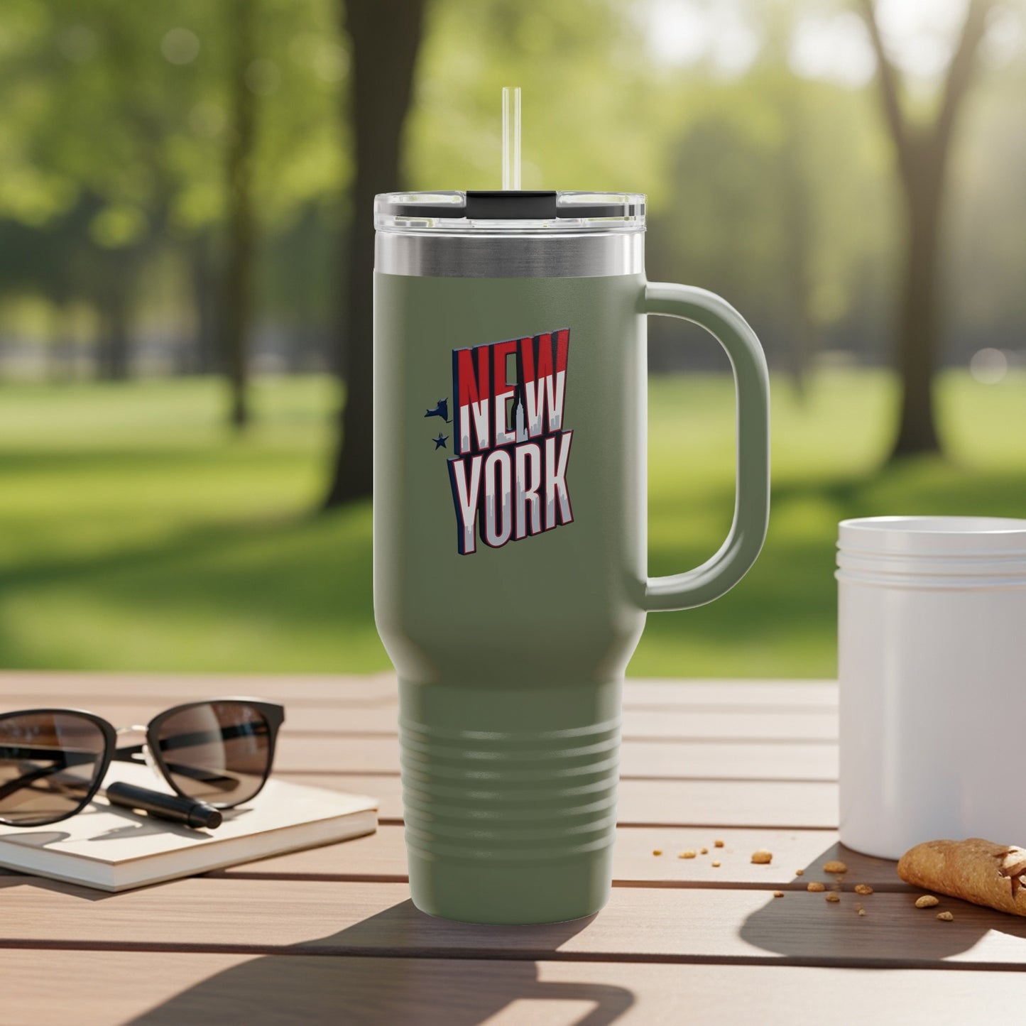 Olive green tumbler with "New York" text and handle, outdoors.