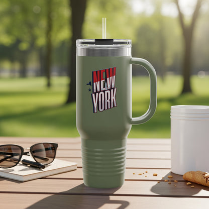 Olive green tumbler with "New York" text and handle, outdoors.