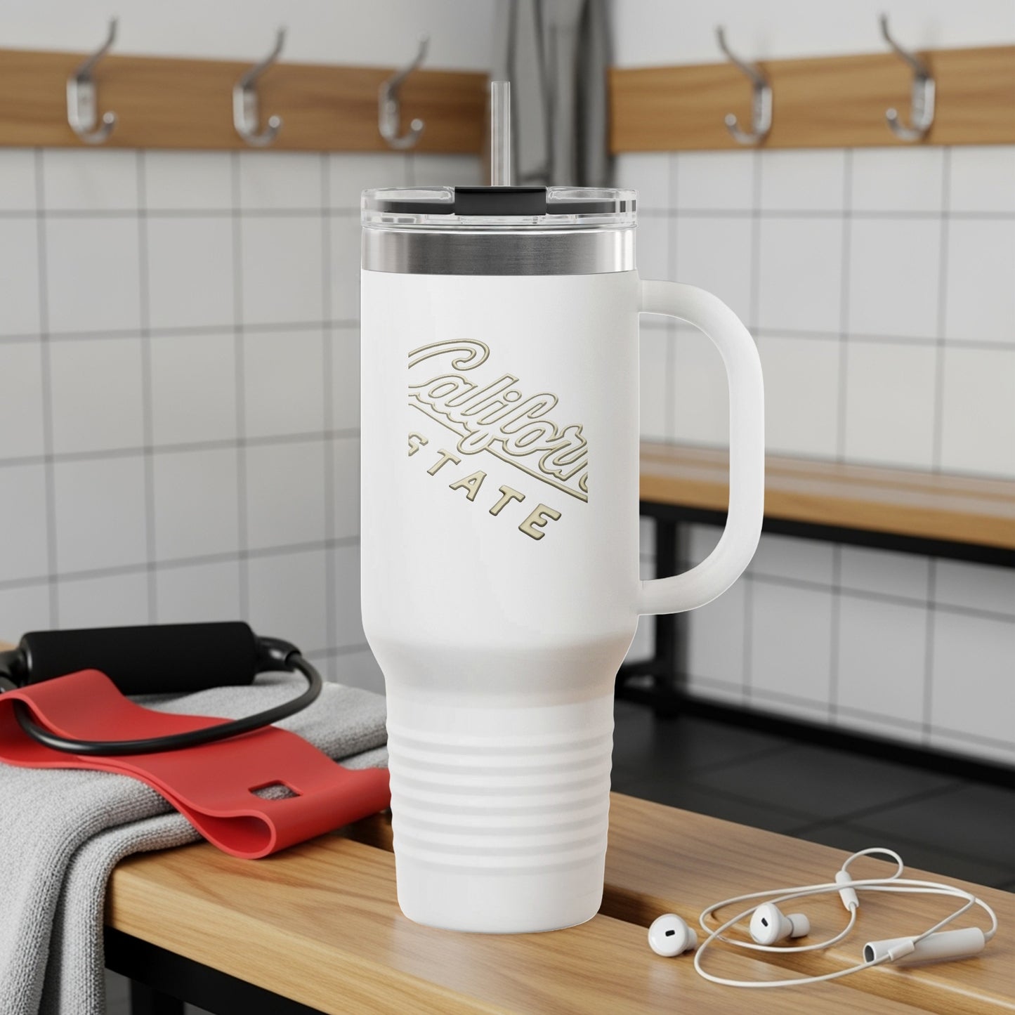 White travel tumbler with "California State" logo in gold, resting on gym bench.