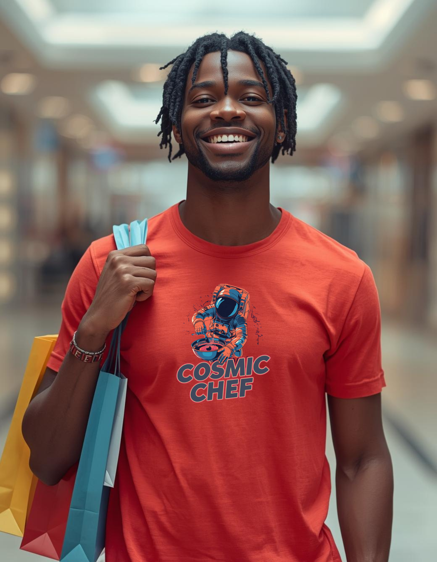 Man wearing a red 'Cosmic Chef' t-shirt holding shopping bags in a blurred indoor setting