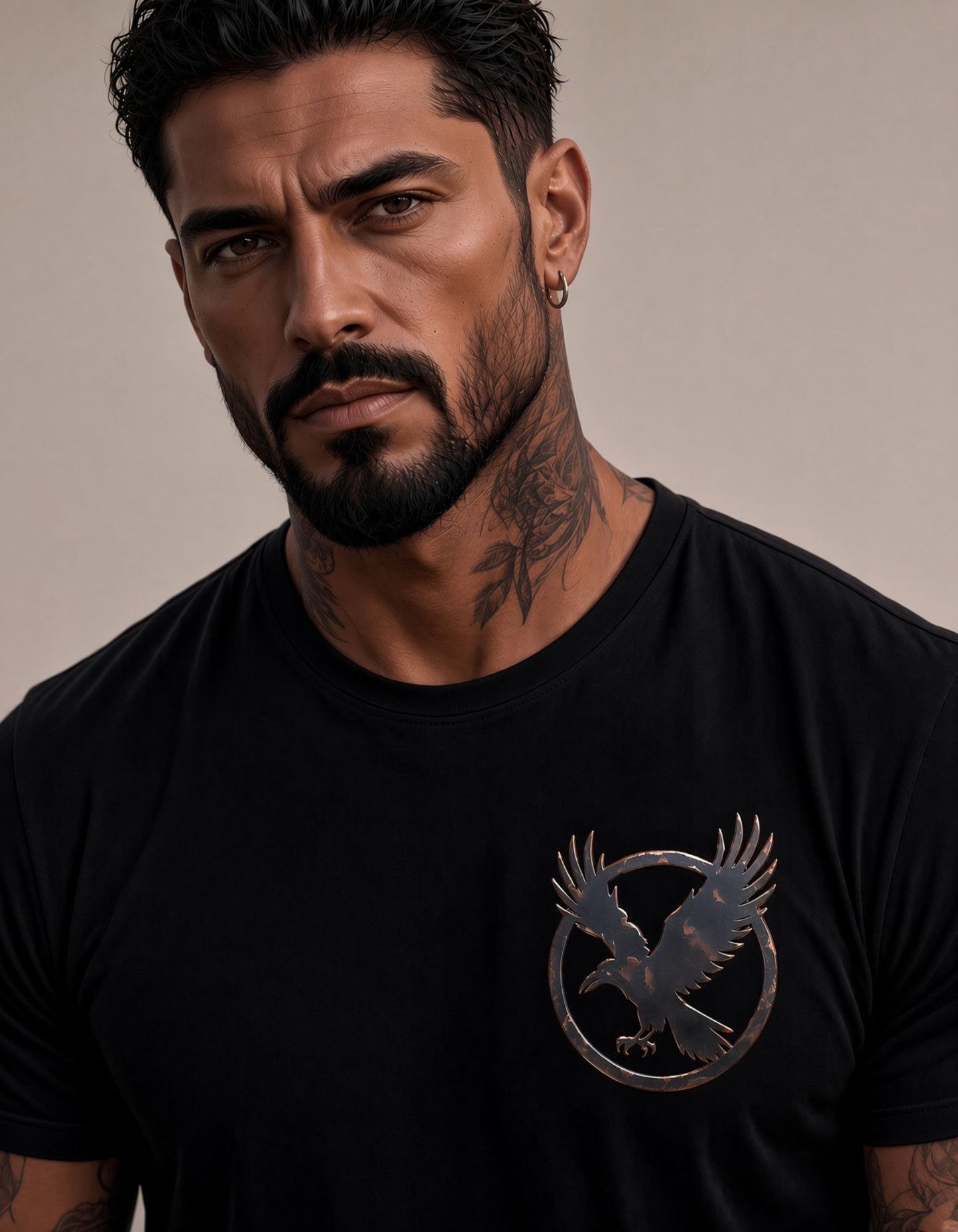 A close-up of a man wearing a black crew-neck t-shirt with a metallic bronze raven graphic on the left chest