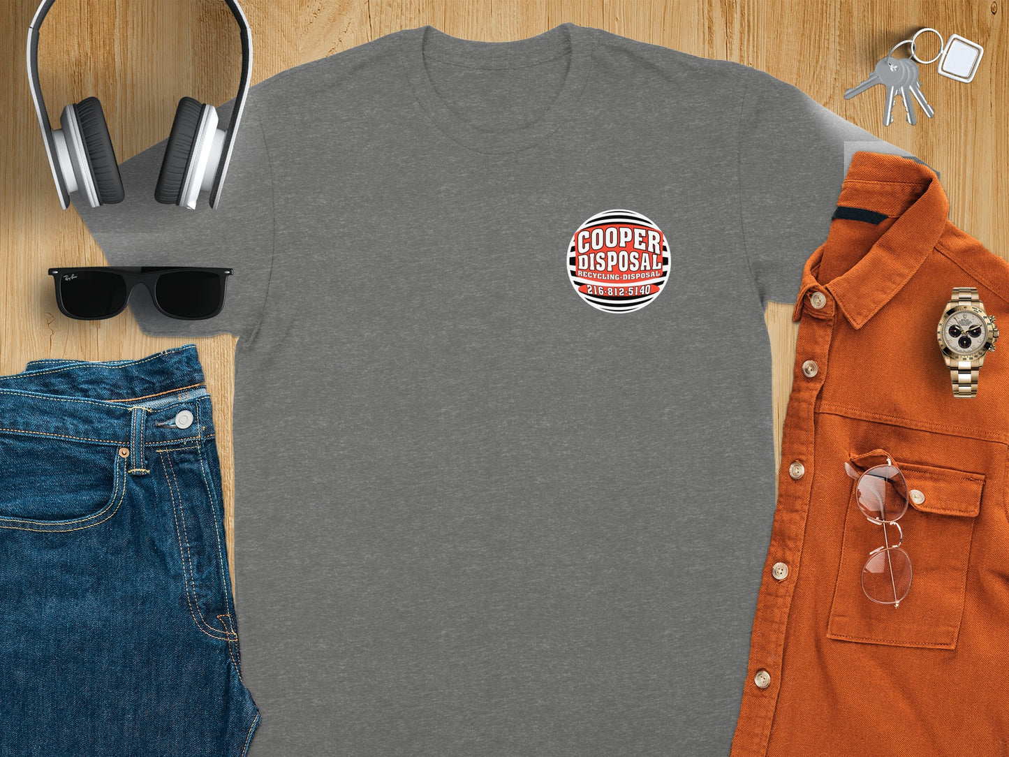 Gray t-shirt with "Cooper Disposal" logo, displayed with jeans, headphones, and sunglasses.
