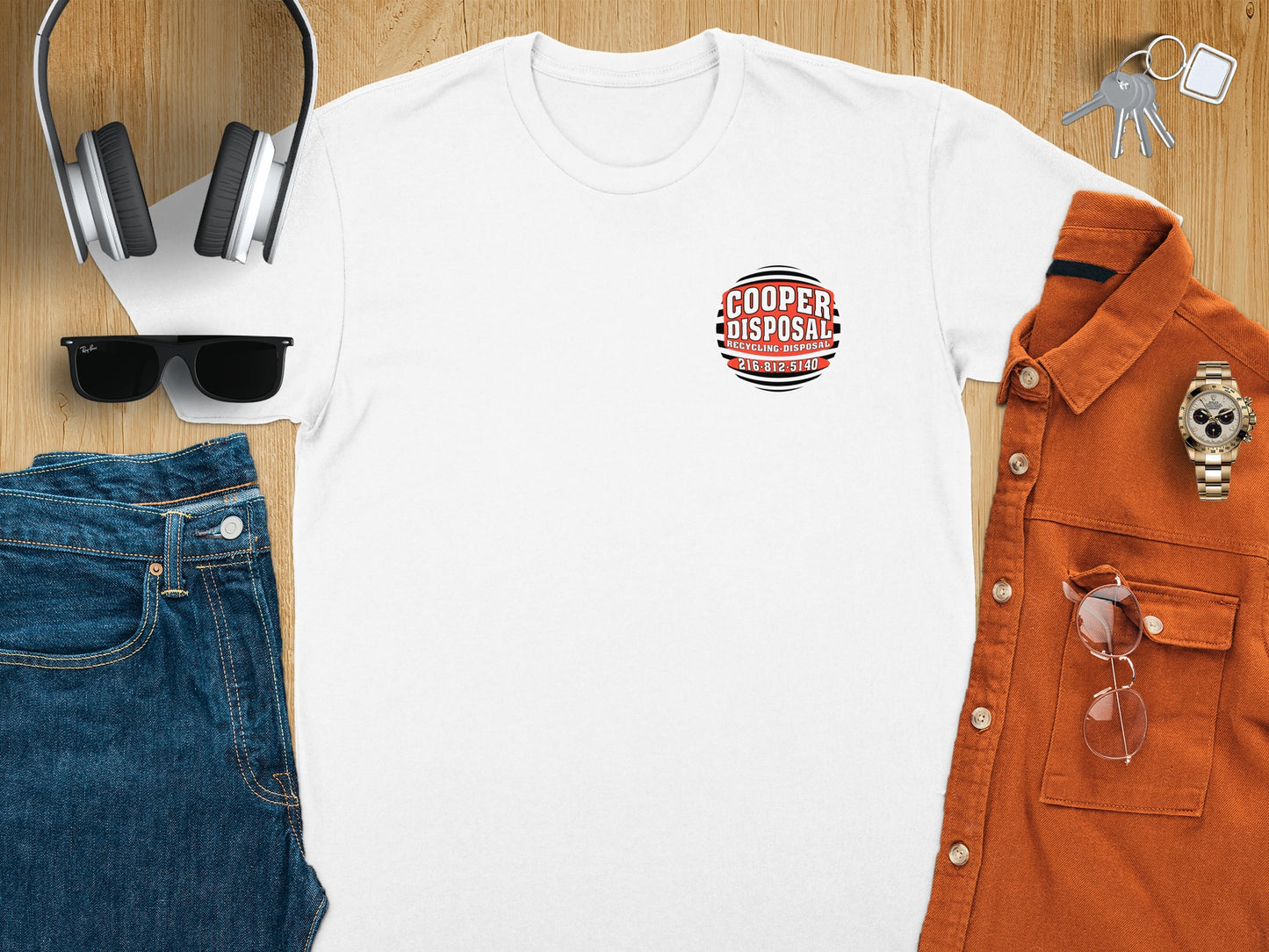 White t-shirt with Cooper Disposal logo, headphones, sunglasses, and clothing laid out.