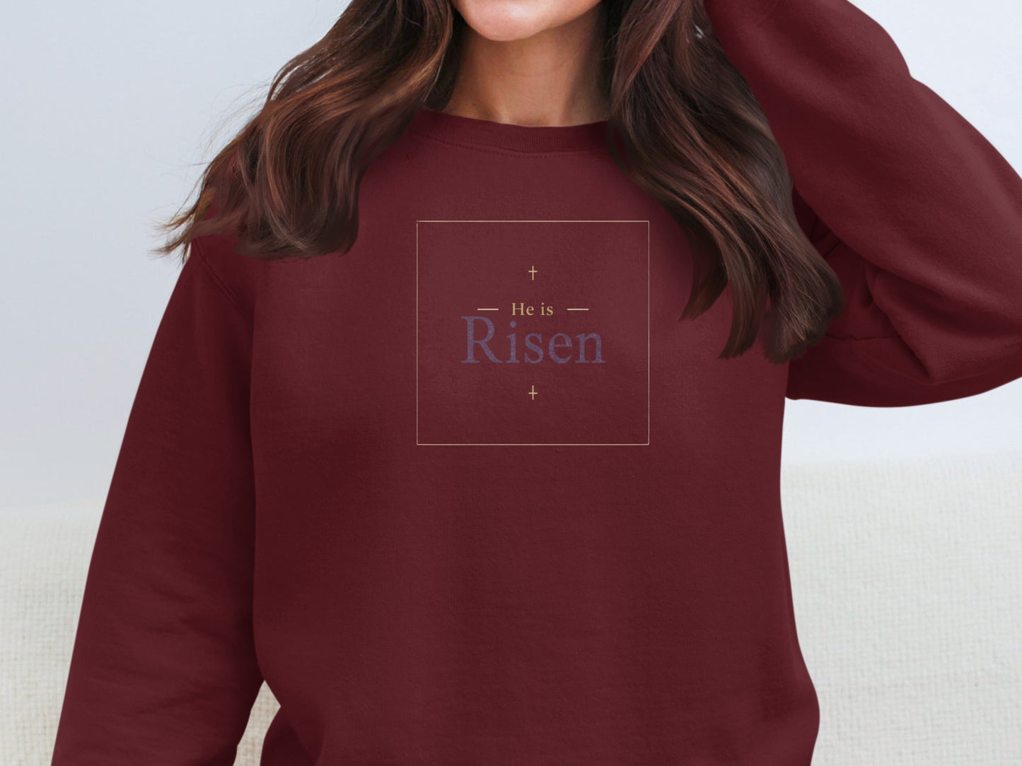 Burgundy sweatshirt with "He is Risen" text and crosses.