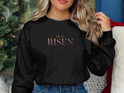 Black sweatshirt with "He is RISEN" text in gradient purple and pink.