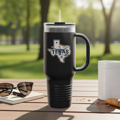 Black travel mug with Texas outline logo and handle, on outdoor table.