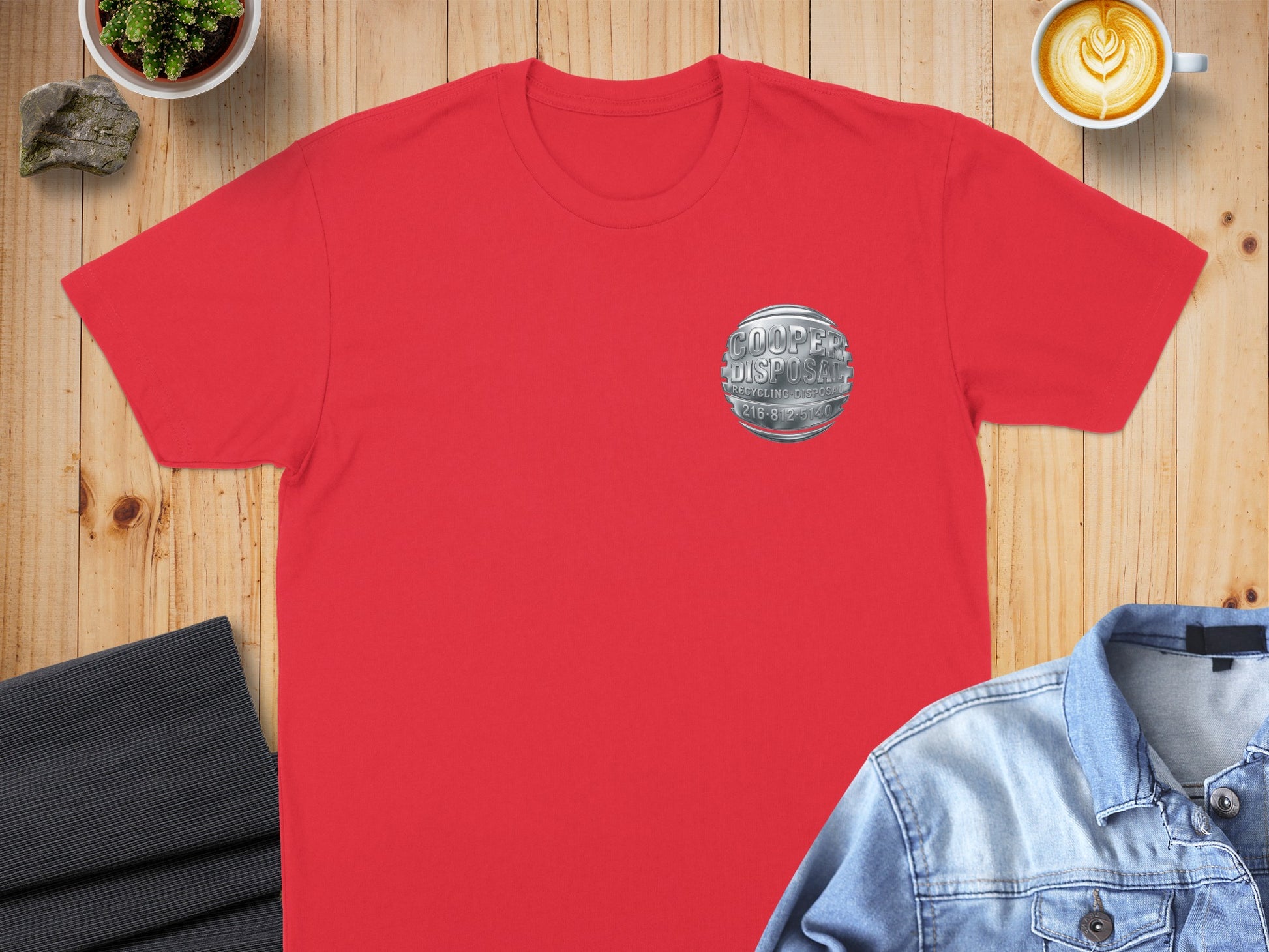 Red t-shirt with "Cooper Disposal" logo, flat lay with coffee and jeans.
