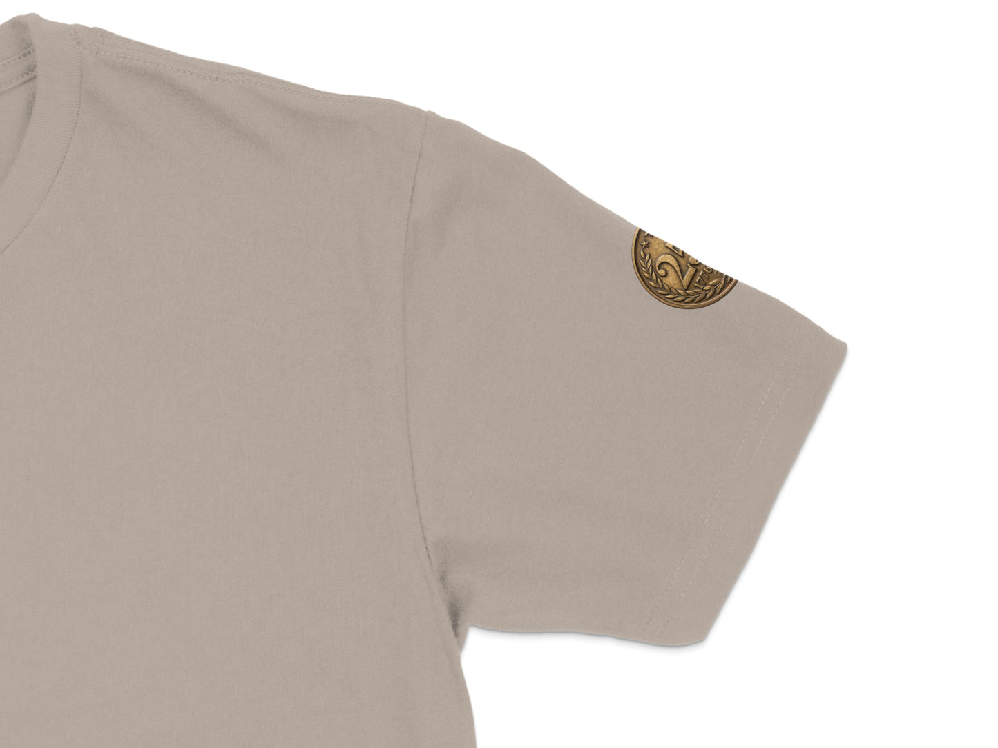 Tan t-shirt sleeve with gold emblem on the cuff.