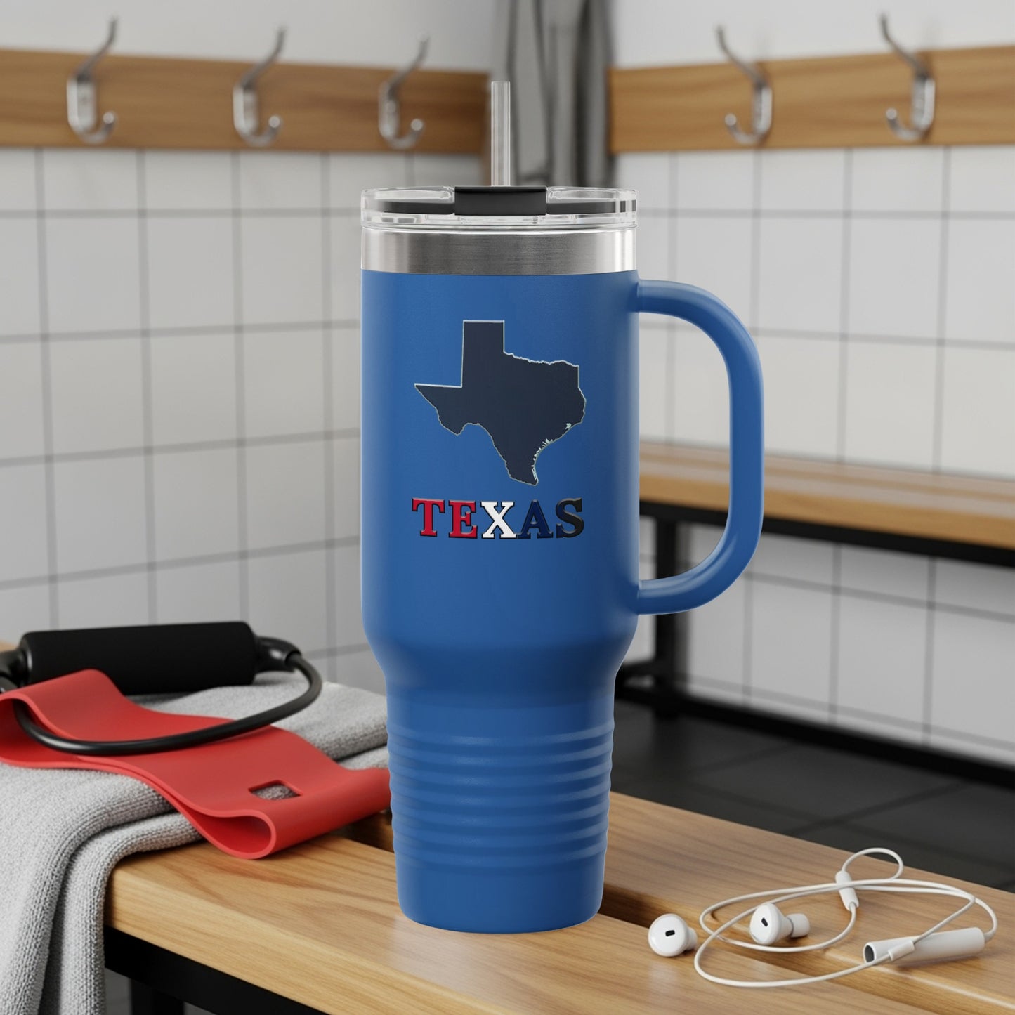 Blue Texas travel mug with handle and straw, resting on a bench.