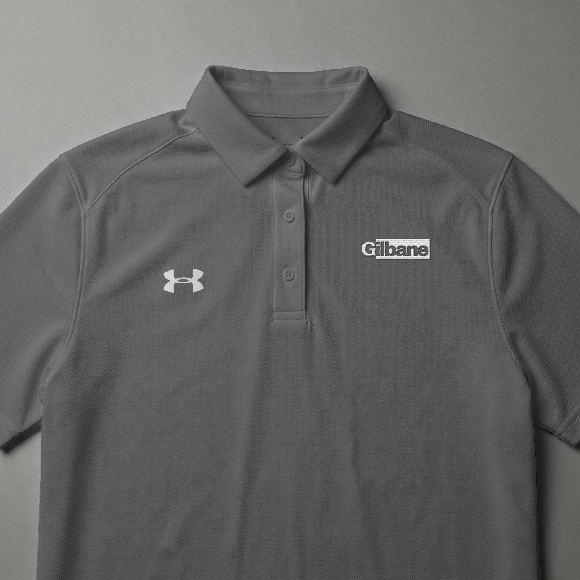 Gray Under Armour polo shirt with Gilbane logo on chest.