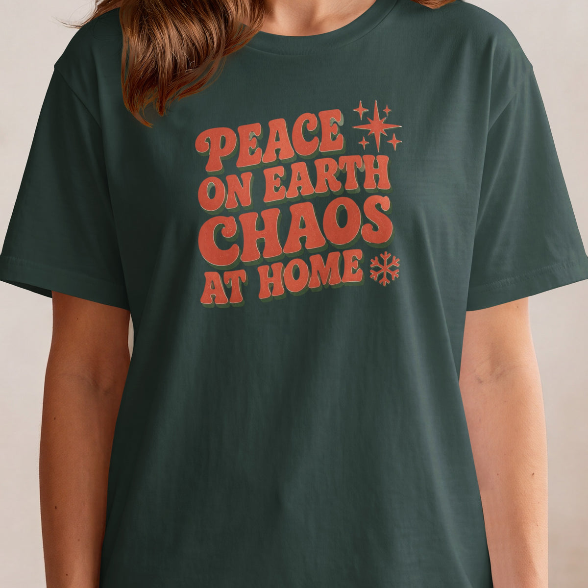 Dark green t-shirt with orange text: "Peace on Earth Chaos at Home".