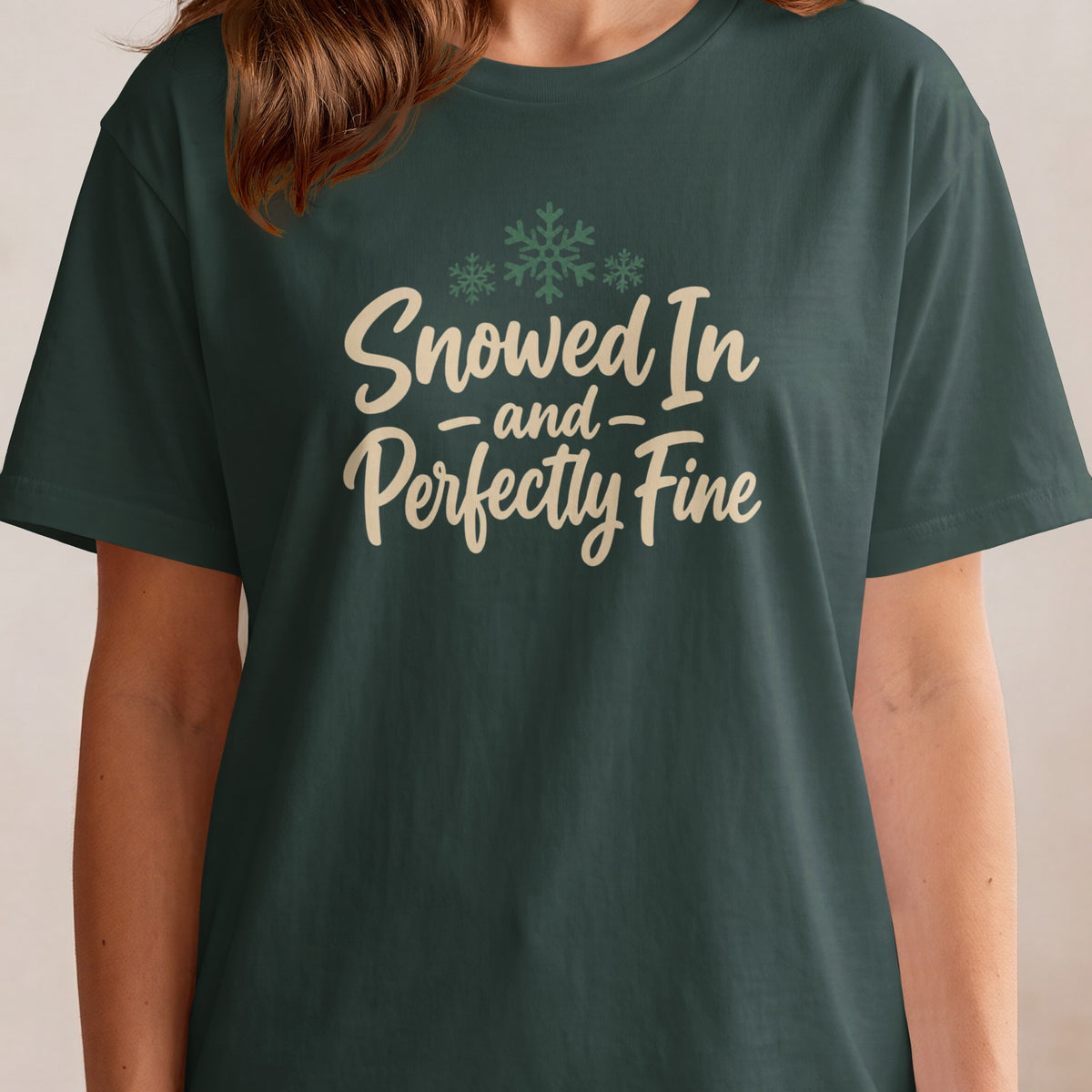 Dark green t-shirt with "Snowed In and Perfectly Fine" text and snowflakes.