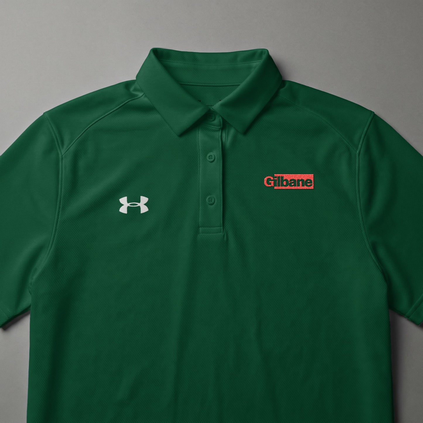 Green Under Armour polo shirt with Gilbane logo on the chest.