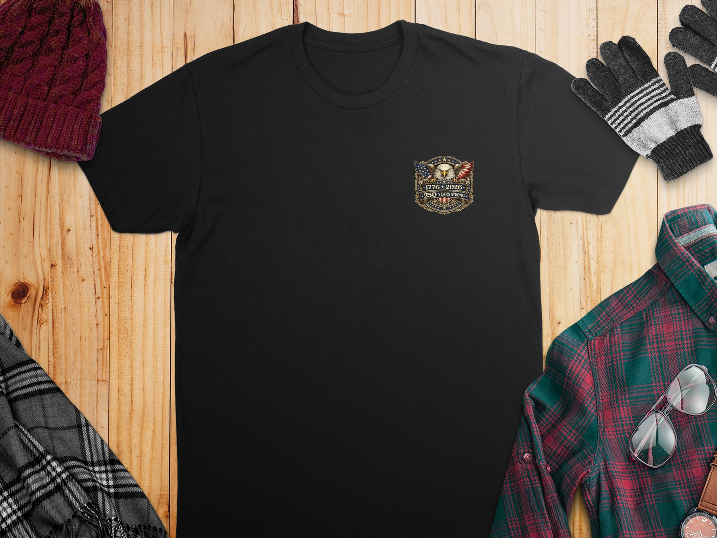 Black t-shirt with patriotic emblem and plaid shirt, gloves, and hat arrangement.