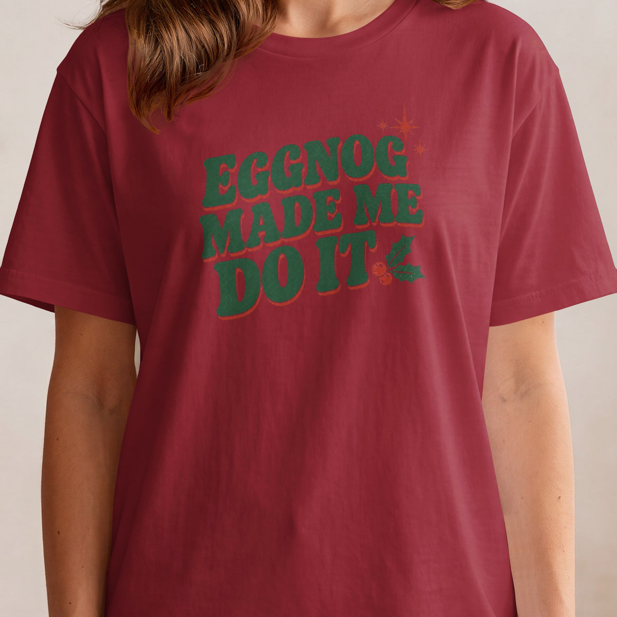 Maroon t-shirt with green text "EGGNOG MADE ME DO IT" and holly accents.